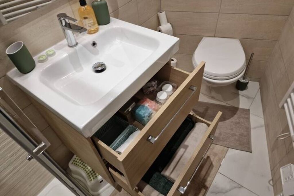 Un baño con lavamanos blanco, inodoro y un mueble de madera con cajones.