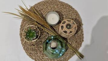 A round woven mat with a candle, a glass container, and dried grass.