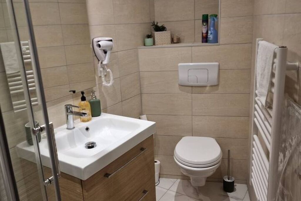 Une salle de bain avec un lavabo blanc, des toilettes, un sèche-mains et un porte-serviettes.