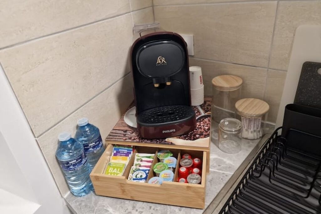 A kitchenette with a coffee maker, water bottles, a food storage box, and a coffee machine.