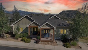 A two-story house with a stone foundation, numbered 305 and 301, surrounded by a landscaped garden with small shrubs and a gravel pathway. - Modern Mountain Retreat/Incredible Mountain Views/Stylish Kitchen/Spotless (Estes Park)