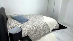 A bedroom with a bed, a bedside table with a lamp, and a patterned bedspread.