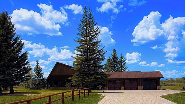 A paved pathway leading to a building with a brick facade, surrounded by trees and a clear sky. - Pinedale's Mountain Vista (Pinedale)