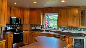 A kitchen with wooden cabinets, a stainless steel refrigerator, a stove, and a sink. - Pinedale's Mountain Vista (Pinedale)