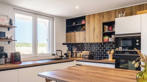 A modern kitchen with a wooden countertop, built-in appliances, and a view through the window. - Hossegor Les Semis in front of the Gravière dune (Soorts-Hossegor)