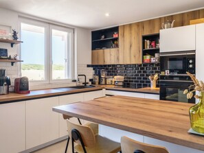 A modern kitchen with a wooden countertop, built-in appliances, and a view through the window.