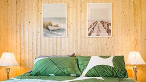 Una habitación con paneles de madera, una cama, dos lámparas y dos cuadros colgados en la pared.