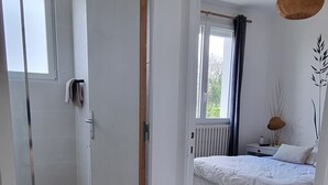 A bedroom with a bed, a bedside table, a lamp, and a window with curtains. - Pretty and bright renovated house in the center of Trégunc with enclosed garden (Trégunc)