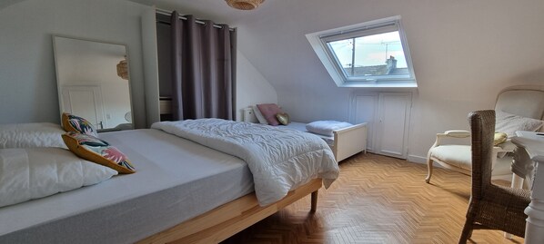Une chambre avec deux lits, une fenêtre, une chaise et une armoire.