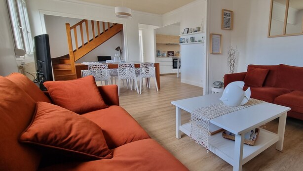 A living room with a sofa, a coffee table, and a TV. There is a staircase leading to a kitchen area. - Pretty and bright renovated house in the center of Trégunc with enclosed garden (Trégunc)