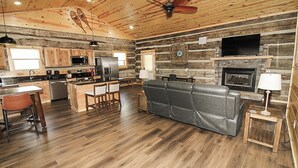 A rustic cabin interior with a kitchen, dining area, and living room.