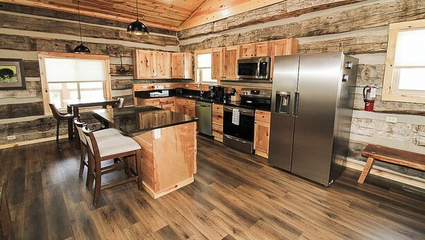 A modern kitchen with wooden cabinetry, a stainless steel refrigerator, and a central island with seating.