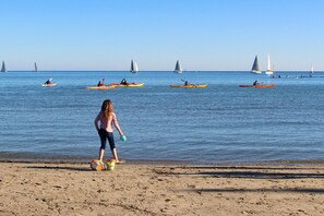 Ein Strand mit Kajaks und Segelbooten auf dem Wasser.
