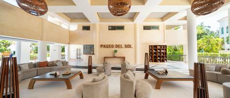 A spacious lobby with a high ceiling, large windows, and a central seating area with sofas and tables.