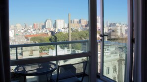 Ein Balkon mit Tisch und Stühlen mit Blick auf eine Skyline aus Gebäuden und Bäumen.