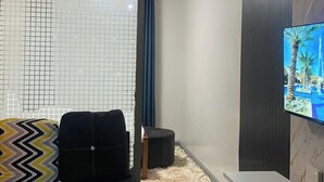 Ein modernes Wohnzimmer mit einer Eckcouch, einem flachbildfernseher an der Wand und einem Couchtisch.