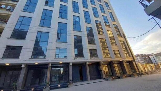 Ein mehrstöckiges Gebäude mit moderner Architektur, das große Fenster und eine glatte Fassade aufweist.
