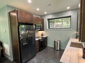 A modern kitchen with stainless steel appliances, a window with a view of greenery, and a marble countertop. - Secluded, hot tub, river, Mtn Views, Brand new (Marion)