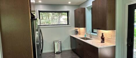 A modern kitchen with built-in cabinets, a stainless steel refrigerator, and a window providing natural light.