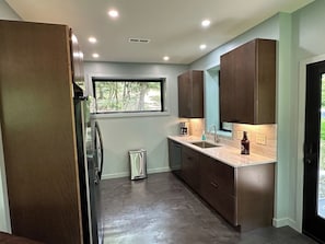 A modern kitchen with built-in cabinets, a stainless steel refrigerator, and a window providing natural light. - Secluded Mountain Escape | River • Hot Tub • Waterfalls • Mountain Views (Marion)