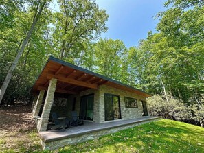 A modern outdoor structure with a stone facade, wooden beams, and a covered patio area. - Secluded Mountain Escape | River • Hot Tub • Waterfalls • Mountain Views (Marion)