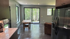 A kitchen with a large refrigerator, a dining table with chairs, and a sliding glass door leading to a deck. - Secluded Mountain Escape | River • Hot Tub • Waterfalls • Mountain Views (Marion)