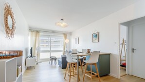 Um quarto moderno e bem iluminado, com uma mesa de jantar, cadeiras e uma televisão.