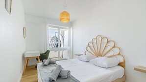 Quarto moderno com cama, escrivaninha e cadeira suspensa.