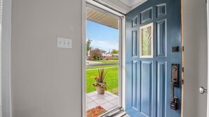 A blue door with a glass panel, a potted plant, and a doormat. - Elegant, Artsy Home in N. Royal Oak! (Royal Oak)
