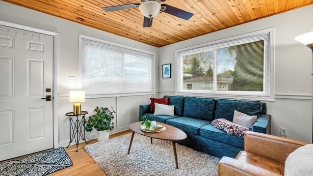 A cozy living room with a wooden ceiling, a blue sofa, a coffee table, and a side table with a lamp. - Elegant, Artsy Home in N. Royal Oak! (Royal Oak)