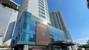 A modern hotel with a prominent Marina Suites sign, featuring a glass facade and a curved design. - Ocean Vista Marina Suites Nha Trang (Nha Trang)