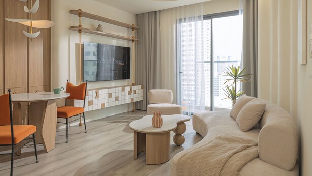 A modern living room with a flat-screen TV, a dining table with chairs, a sofa, and a ceiling fan. - Ocean Vista Marina Suites Nha Trang (Nha Trang)