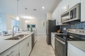 A modern kitchen with stainless steel appliances, a central island, and pendant lighting.