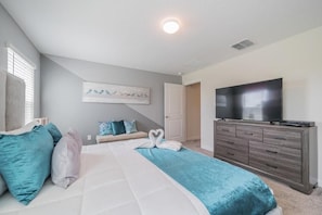 A bedroom with a bed, a dresser, a television, and a wall art piece.
