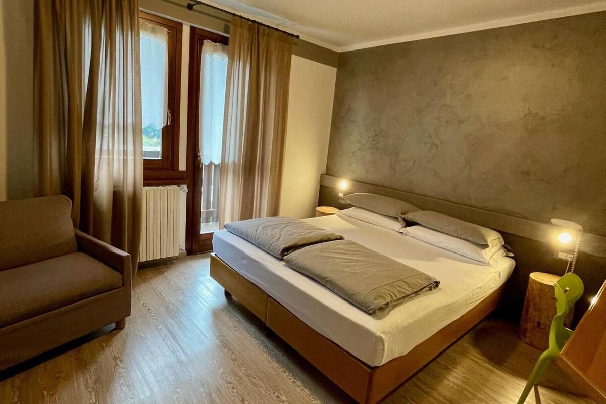 A bedroom with a bed, a chair, a bedside table, and a lamp.