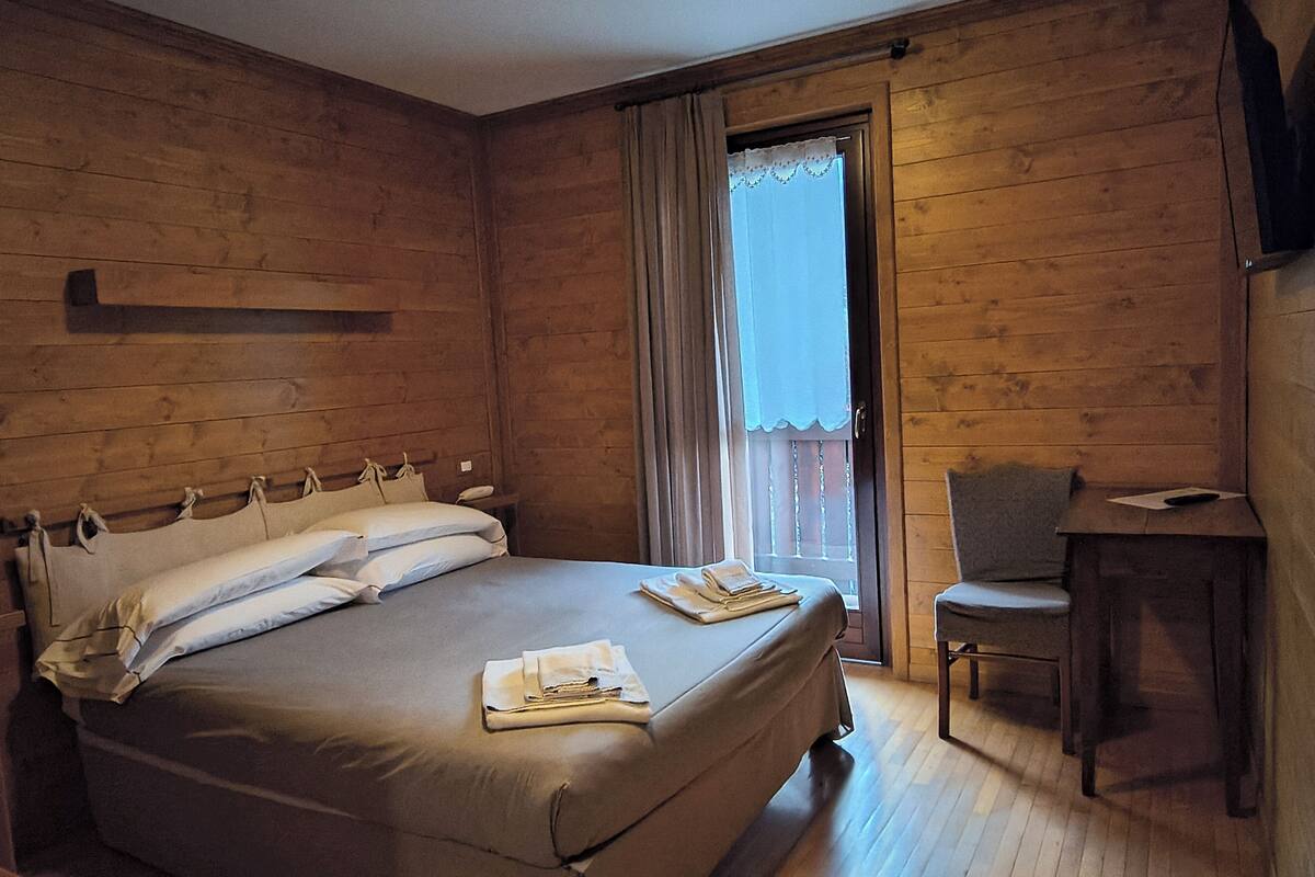 A wooden room with a bed, a desk, and a chair.