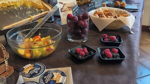 A breakfast buffet with various food items including fruits, pastries, and yogurt. - Hotel Sorriso  (Temu)