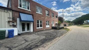 A two-story brick building with a blue awning, a garage door, and a small porch.