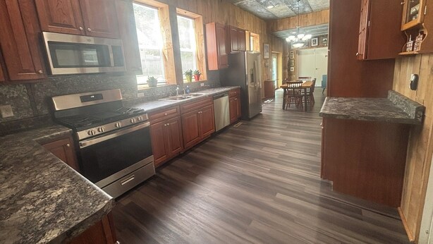 A kitchen with wooden cabinets, a stainless steel stove, and a microwave. - 1st Floor 2BR Downtown + 2 Parking Spaces (Elkader)