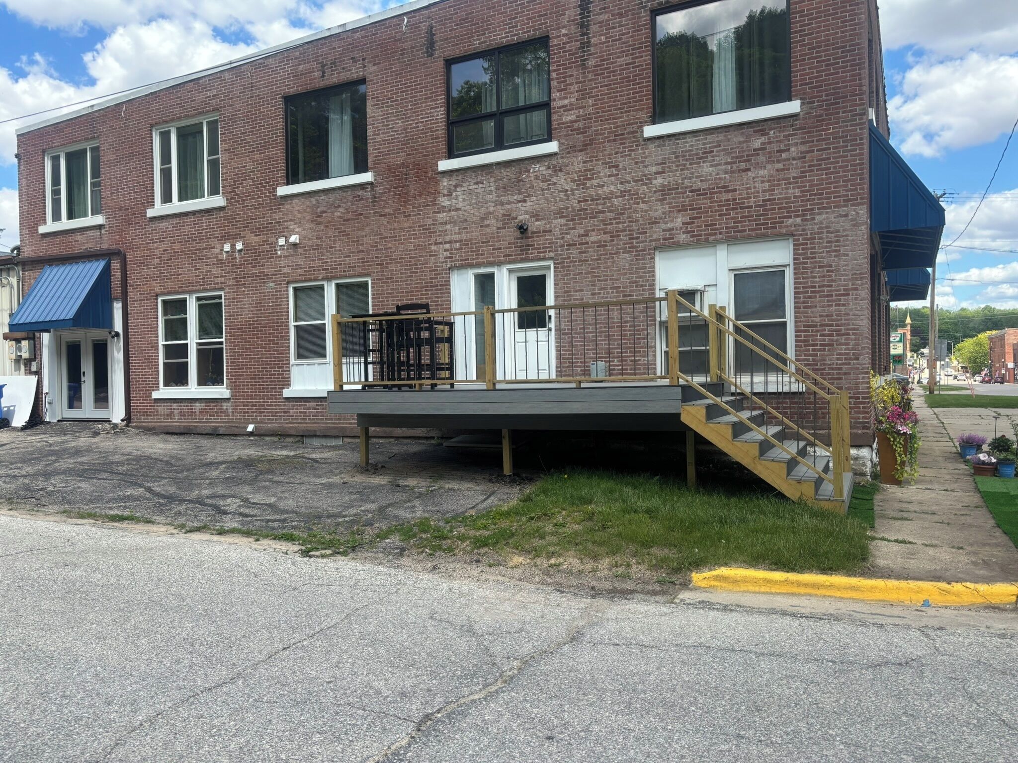 A two-story brick building with a covered outdoor seating area and a staircase leading to the entrance.