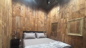 A wooden-paneled bedroom with a bed, two bedside tables, and a framed picture on the wall. - 1st Floor 2BR Downtown + 2 Parking Spaces (Elkader)