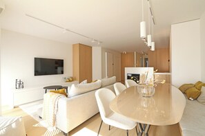 Un salon moderne comprenant un canapé, une table à manger et un téléviseur fixé au mur.