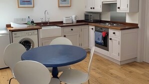 A modern kitchen with a skylight, white cabinets, a round table, and a washing machine.