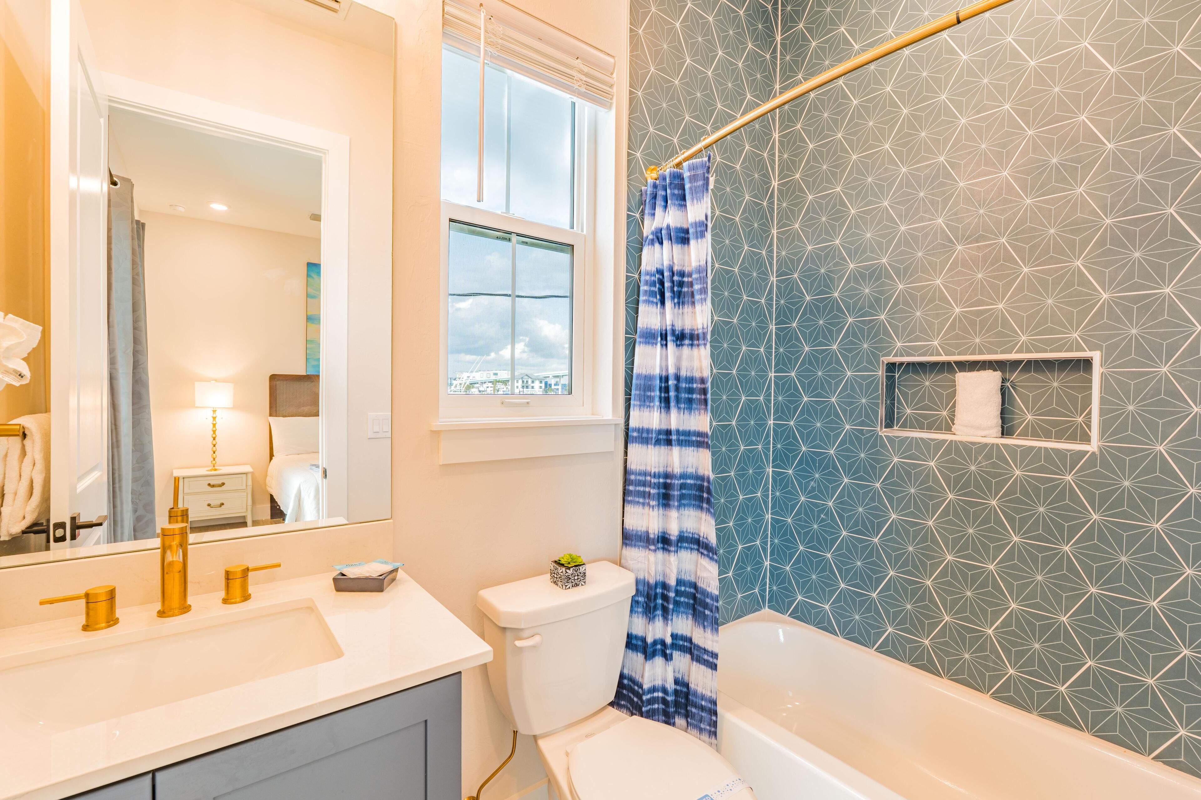 A bathroom with a white sink, gold faucets, a toilet, and a shower curtain.
