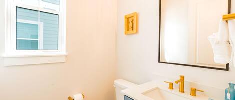 A bathroom with a toilet, sink, and mirror.