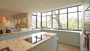 A modern kitchen with a large island, built-in appliances, and a large window providing a view of the outdoors. - Villa in Het Zoute Near Zeedijk Promenade (Knokke-Heist)