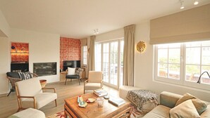 A spacious living room with a sofa, armchairs, a coffee table, and a fireplace. - Villa in Het Zoute Near Zeedijk Promenade (Knokke-Heist)