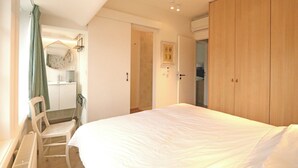 A bedroom with a bed, a chair, a wardrobe, and a door leading to a bathroom. - Villa in Het Zoute Near Zeedijk Promenade (Knokke-Heist)