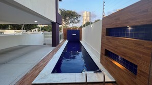 A modern outdoor swimming pool with a wooden deck and a concrete border.