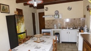 A compact kitchen with a dining area, featuring a microwave, stove, sink, and a small refrigerator. - Purple perigord house (Lanquais)
